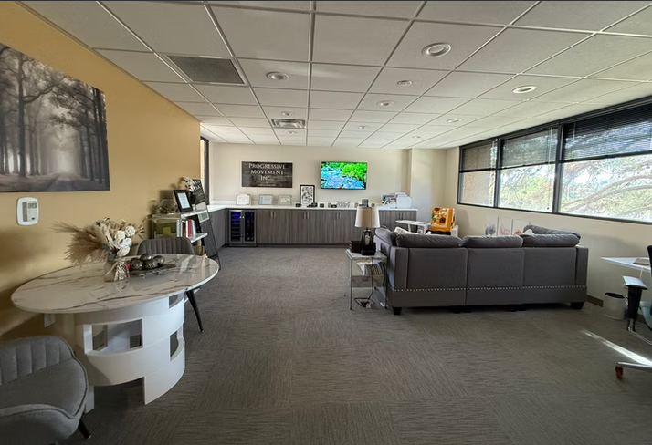 Modern mental health office waiting room with yellow accent wall, seating area, reception desk, and large windows